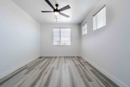 an empty room with wood floors and a ceiling fan