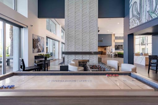 a shuffleboard table in a clubhouse with a fireplace