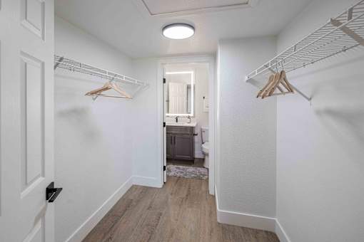 a closet in a bedroom with white walls and wood floors