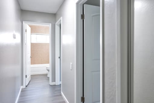 A hallway with a white door and a window.