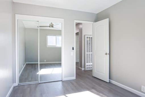 A room with a white door and a mirror on the wall.
