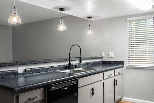 Kitchen island with double sink and pendant lighting at Redwood Cove Apartments, California
