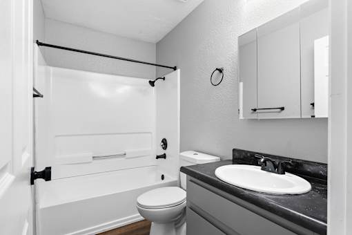 Bathroom with tub shower combo and mirrored medicine cabinet at Redwood Cove Apartments, California