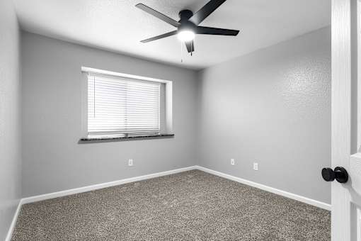 Carpeted bedroom with ceiling fan and window blinds at Redwood Cove Apartments, Chico