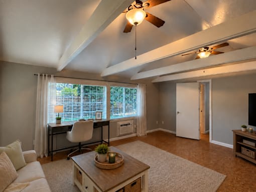 A living room with a white couch, a wooden coffee table, and a ceiling fan.