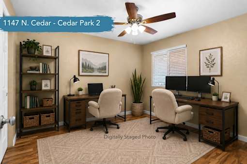 A room with two desks and two chairs, a ceiling fan, and a rug on the floor.