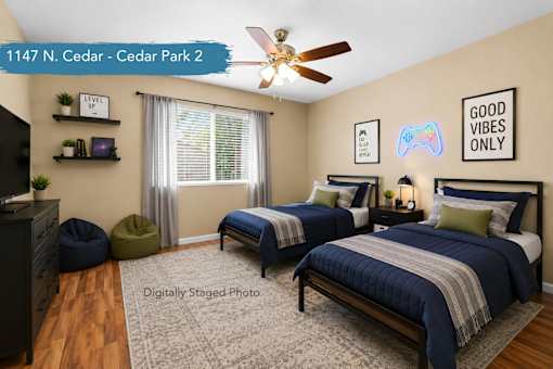 A bedroom with two beds, a ceiling fan, and a "Good Vibes Only" sign on the wall.