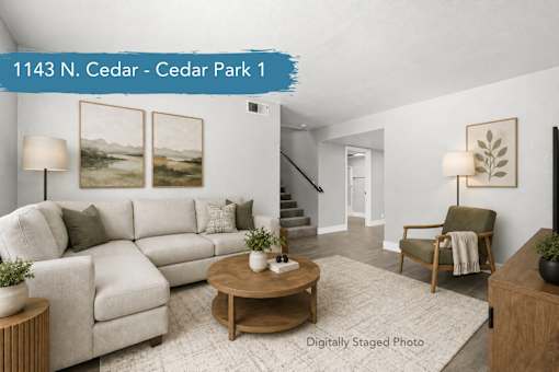 A living room with a white couch, a coffee table, and a painting on the wall.