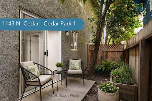 A patio with two chairs and a table with a potted plant on it.