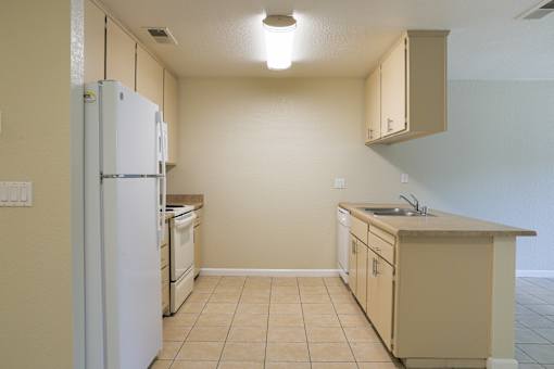 an empty kitchen with a refrigerator and a sink at Creekview Homes, Chico, CA, 95928