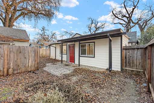 A small house with a red door is surrounded by a wooden fence.at OSM Properties Homes & Apartments, Chico California  