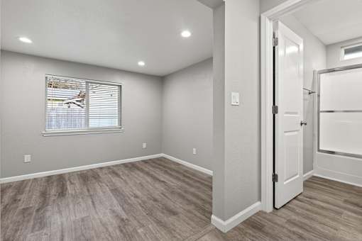A room with a wooden floor and a window with blinds.at OSM Properties Homes & Apartments, Chico, CA 95926  