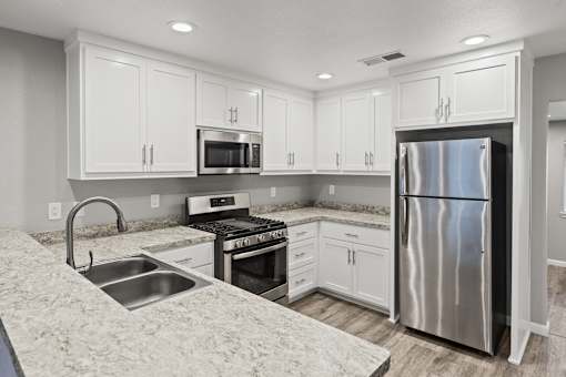 A kitchen with white cabinets and a stainless steel refrigerator.at OSM Properties Homes & Apartments, Chico California  