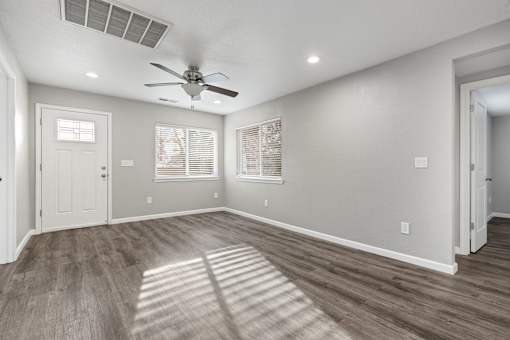 A room with a ceiling fan and wooden flooring.at OSM Properties Homes & Apartments, California  