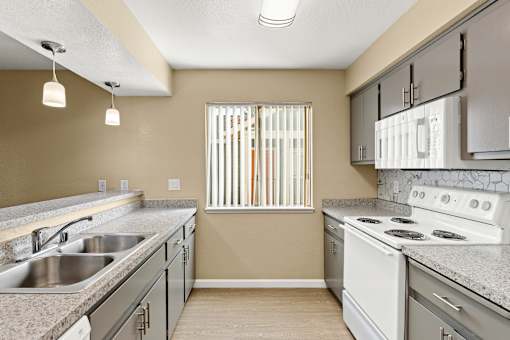 A kitchen with a stove, sink, and cabinets.at Redwood Cove Apartments, Chico, CA  