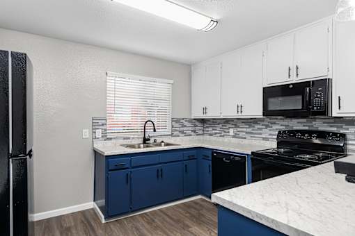 Kitchen with blue lower cabinets and black appliances at Pomona Townhomes Apartments, Chico, CA