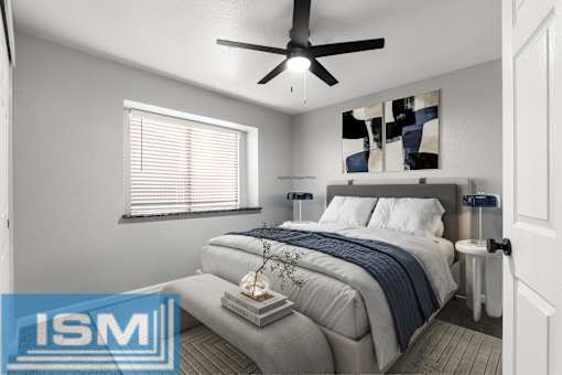 Staged bedroom with gray upholstered bed and abstract art at Redwood Cove Apartments, Chico, CA