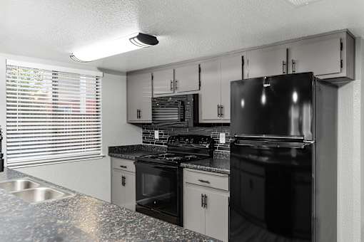 Kitchen with black appliances and granite countertops at Redwood Cove Apartments, California, 95928