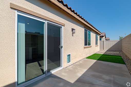 A modern house with a tan exterior and a green lawn in front.