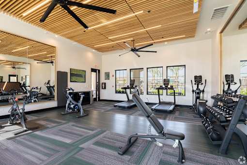 A gym with a variety of equipment including treadmills, stationary bikes, and weight machines.