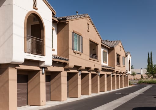 a row of beige buildings with garage doors and balconies