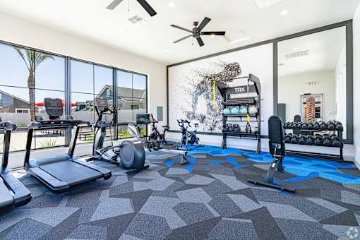 A gym with treadmills, elliptical machines, and a fan.