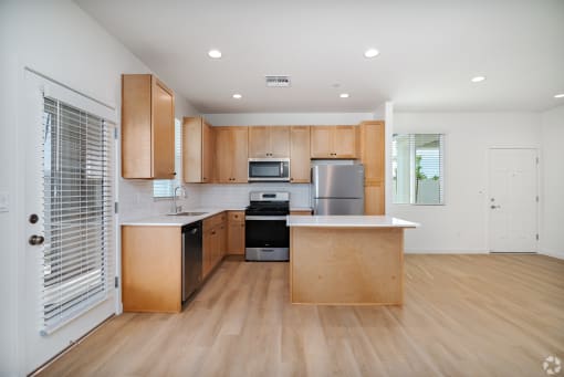a kitchen with wooden cabinets and a large island with a stove and a refrigerator