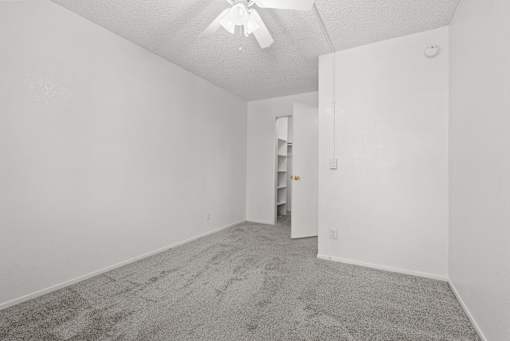 A room with a carpeted floor and a ceiling fan.
