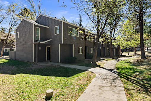 A modern house with a grey facade and a green lawn in front.