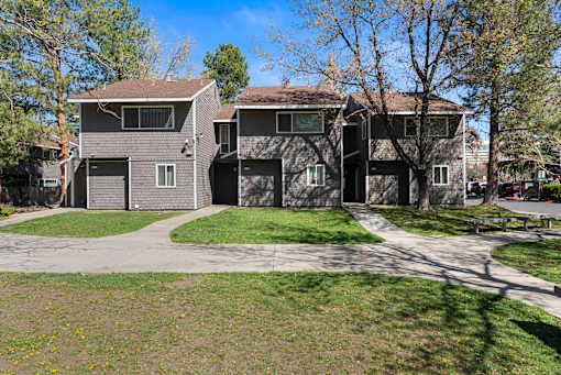 A grey house with a driveway in front.
