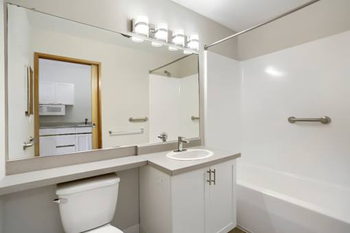 A white bathroom with a toilet, sink, and mirror.