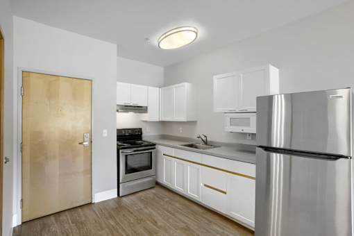 A kitchen with white cabinets and a stainless steel refrigerator.