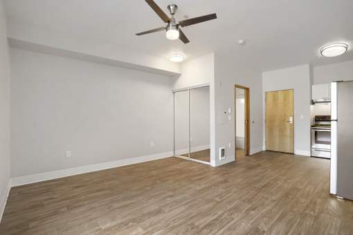 A room with a ceiling fan and wooden flooring.