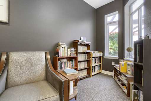 A room with a chair, a bookshelf, and a window.