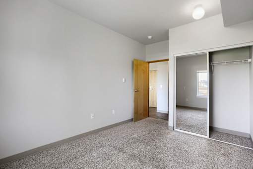 A room with a carpeted floor and a mirrored closet door.