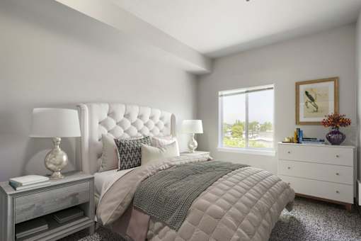 A bedroom with a large bed, a nightstand with a lamp, and a window with a view of trees outside.