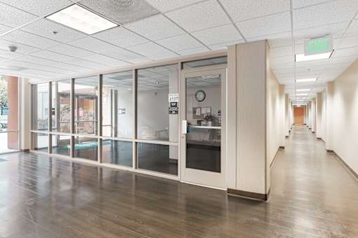A long hallway with a glass door and a green exit sign at Pin Yuen, Sacramento, CA