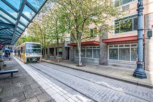 A yellow tram is on a street with a blue pole on the right.