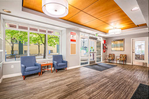 A waiting room with two blue chairs and a table.