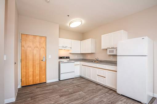 A kitchen with white appliances and wooden floors.