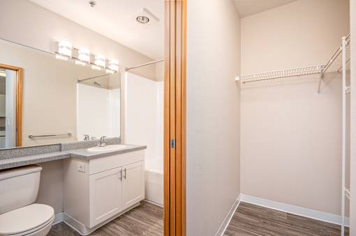 A bathroom with a toilet, sink, mirror, and a walk-in shower.