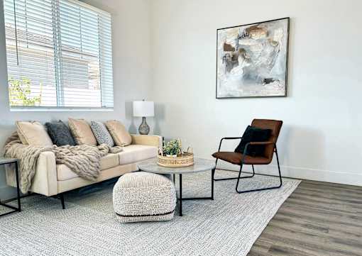 A living room with a beige couch, a chair, a small table, and a painting on the wall at Zora Encanto, Phoenix, 85035