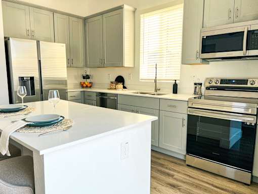 A modern kitchen with a white island and stainless steel appliances at Zora Encanto, Phoenix, AZ