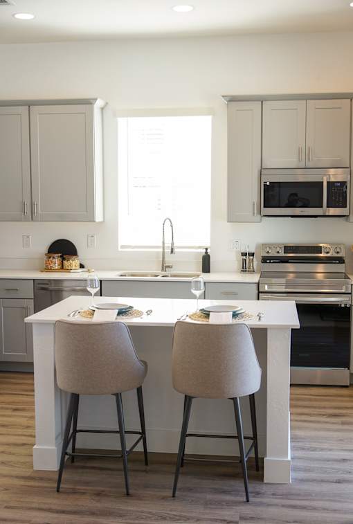 A kitchen with a white countertop and two chairs at Zora Encanto, Phoenix
