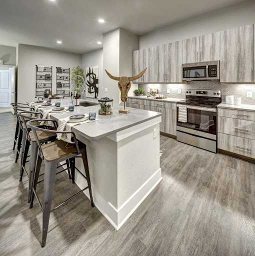 A modern kitchen with a white island and a cow skull as a decoration at Arise Riverside Apartments, Texas
