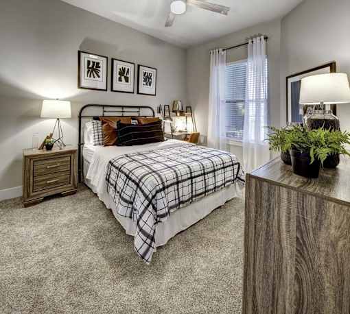 A bedroom with a bed, nightstands, and a plant. at Arise Riverside Apartments, Austin, TX, 78741