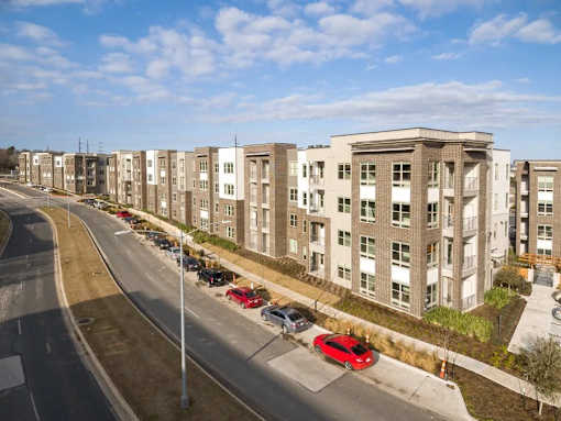 A row of apartment buildings with cars parked in front at Arise Riverside Apartments, Austin, Texas