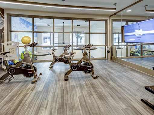 A room with exercise bikes and a TV screen at Arise Riverside Apartments, Texas