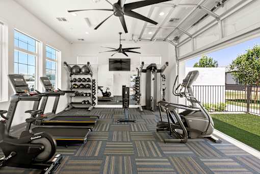 a gym with treadmills and weights and a ceiling fan at Zora Encanto, Arizona 85035