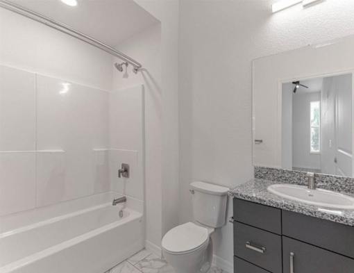 A white bathroom with a toilet, sink, and bathtub.